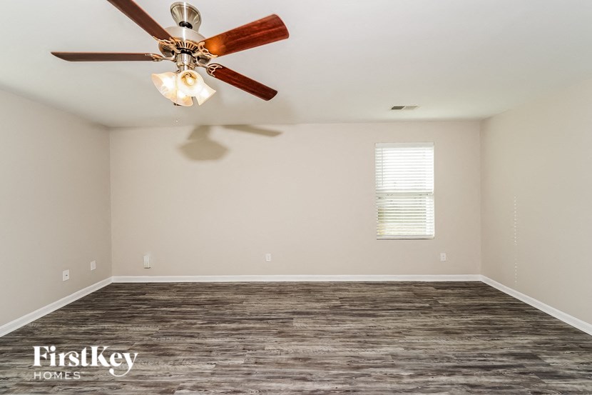 A room with a ceiling fan and wooden flooring.