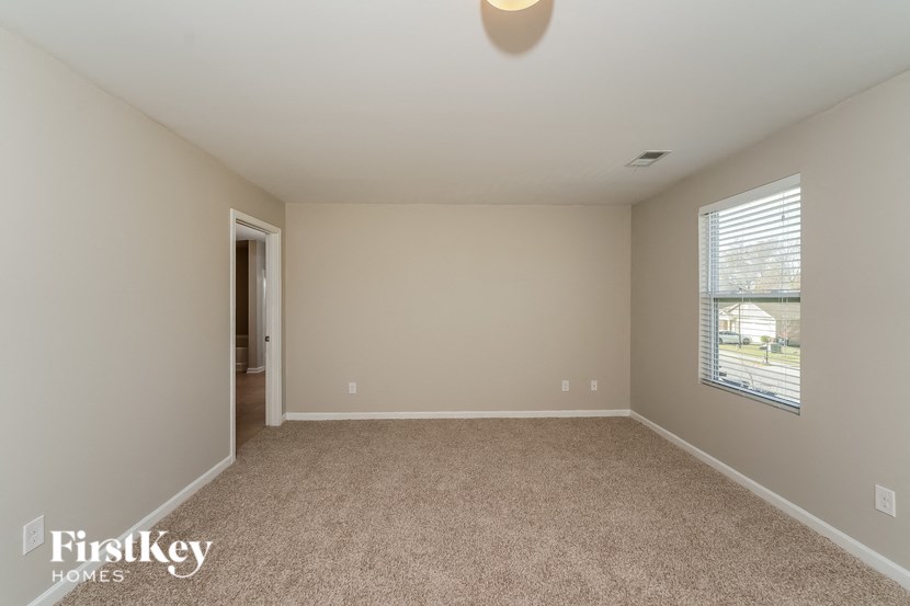 A room with a carpeted floor and a window with blinds.
