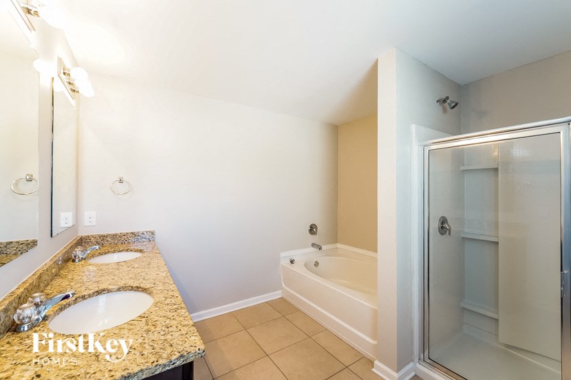 A bathroom with a granite countertop and a walk-in shower.