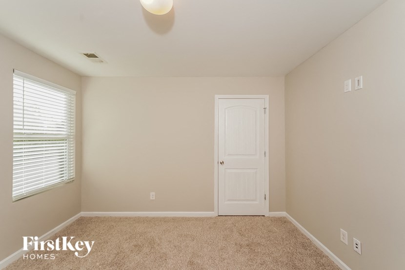 A room with a white door and a window with blinds.