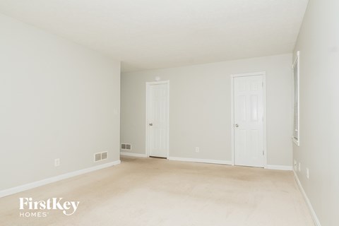 a living room with white walls and a white carpet and two doors