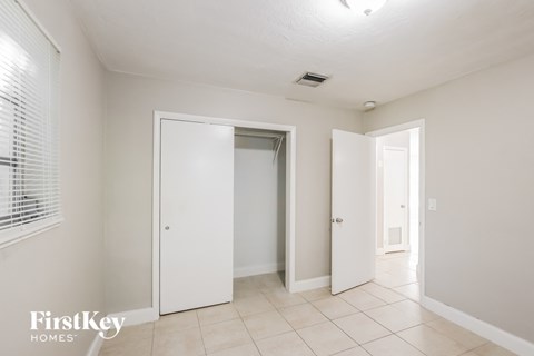 a bedroom with two closets and a tiled floor and white walls and doors