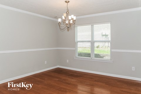 A room with a chandelier and a window with blinds.