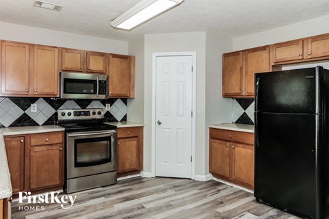 A kitchen with wooden cabinets and a black refrigerator.