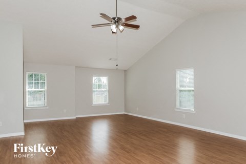 A spacious room with a ceiling fan and wooden flooring.
