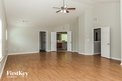A spacious room with wooden floors and a ceiling fan.