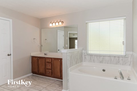 A white bathroom with a tub, sink, and mirror.