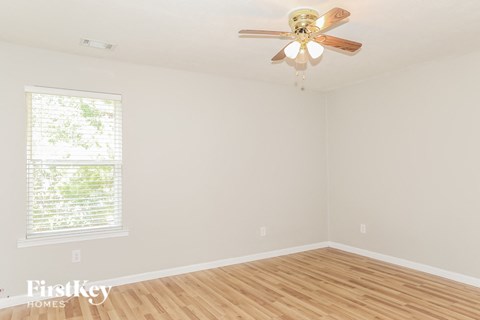 A room with a ceiling fan and a window with blinds.