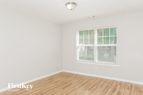 A room with a window covered by white blinds.