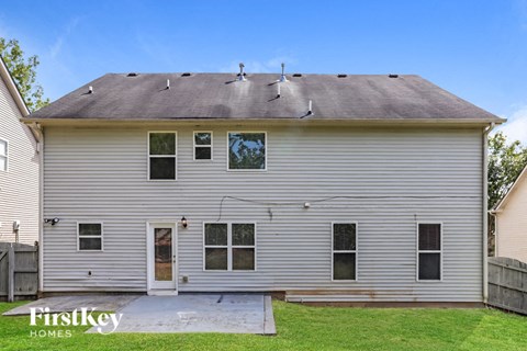 A house with a grey siding and a brown roof with a white door and windows.