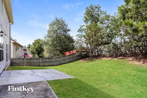 A backyard with a FirstKey Homes sign in the foreground.