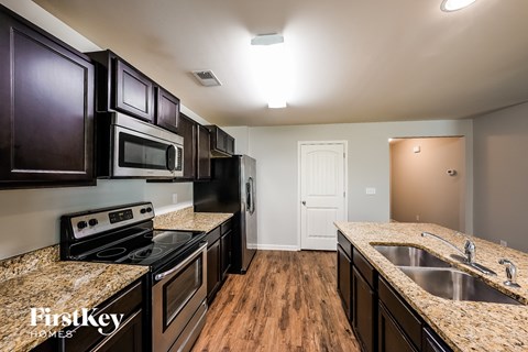 full kitchen with black appliances and granite counter tops at the reserve at walnut creek
