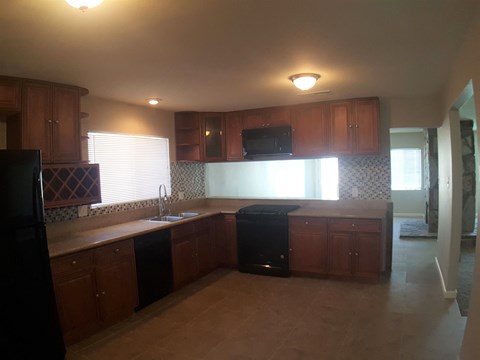 A kitchen with wooden cabinets and a black fridge.