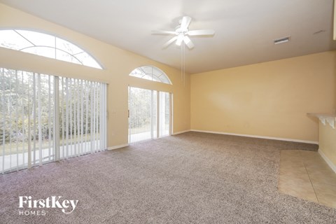 A spacious room with a fan and carpeted floor.