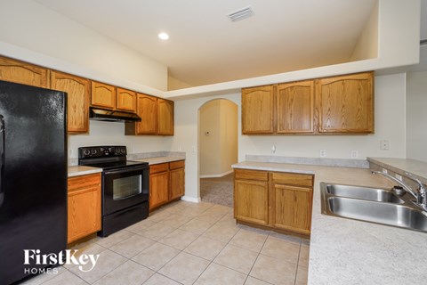 A kitchen with wooden cabinets and a black fridge.