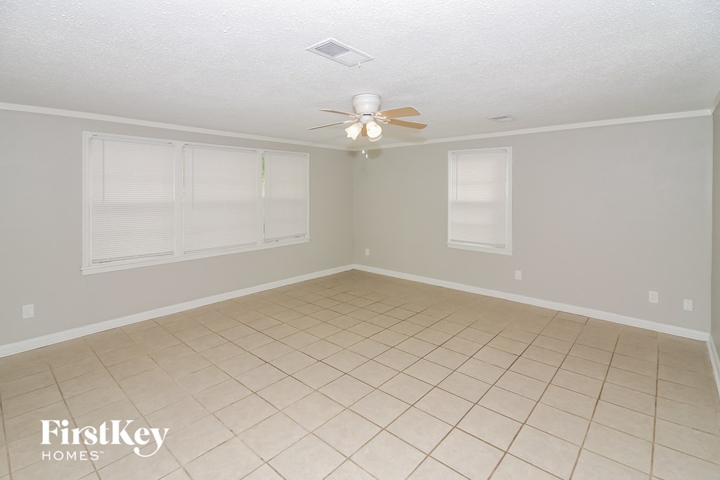 a empty living room with a ceiling fan and two windows