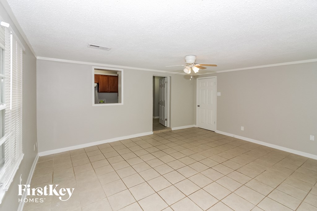an empty living room with a ceiling fan and tiled floor