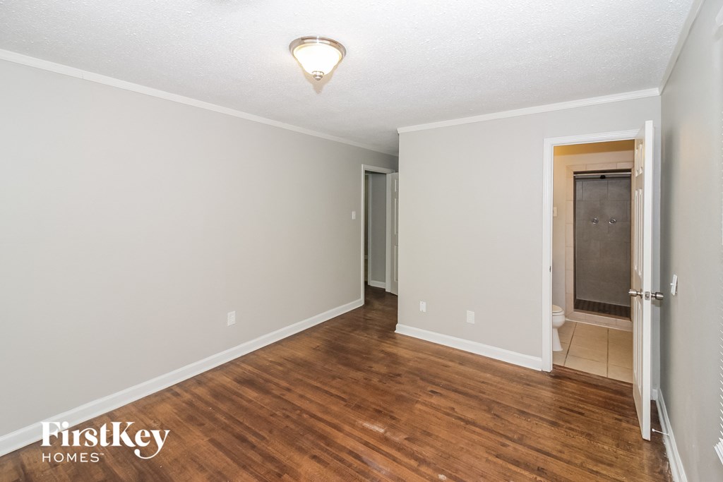 a living room with a hard wood floor and a door to a bathroom