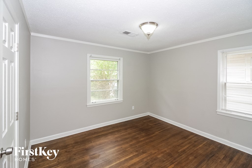 the living room of a house with a hardwood floor and two windows