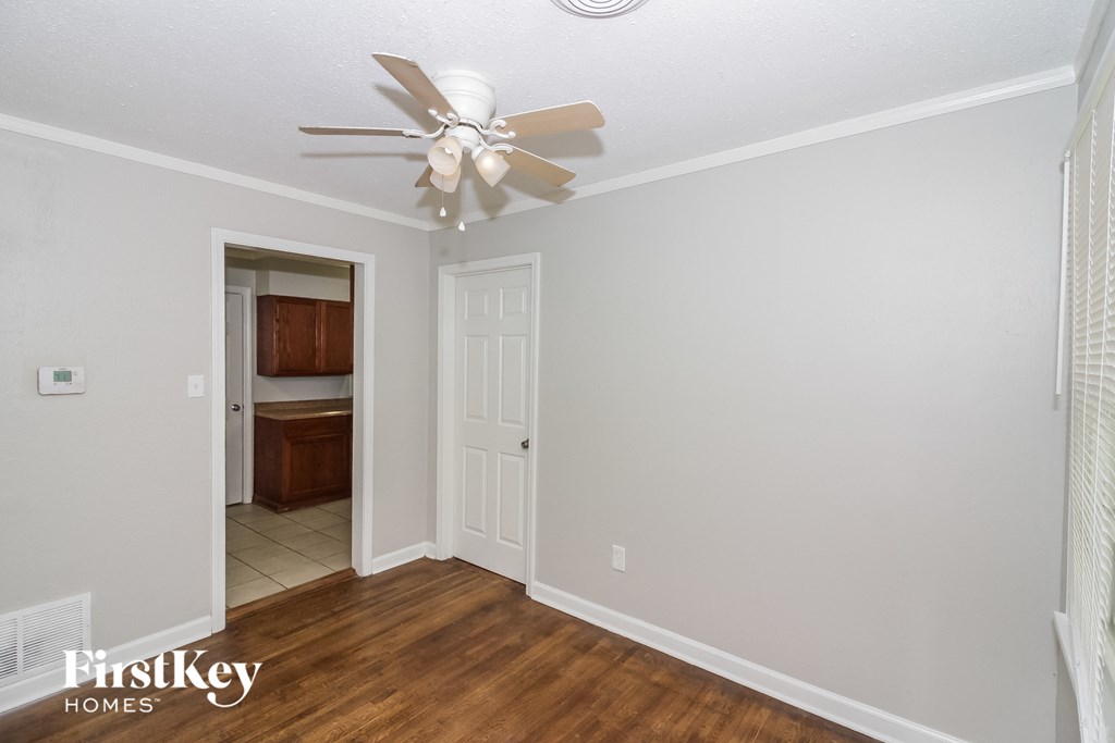 a bedroom with a ceiling fan and a door to a bathroom
