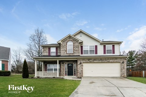 a home with a white garage door and a brick house with pink shutters