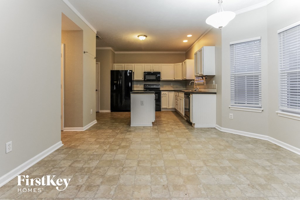 the kitchen and living room of an open floor plan with a kitchen island and refrigerator