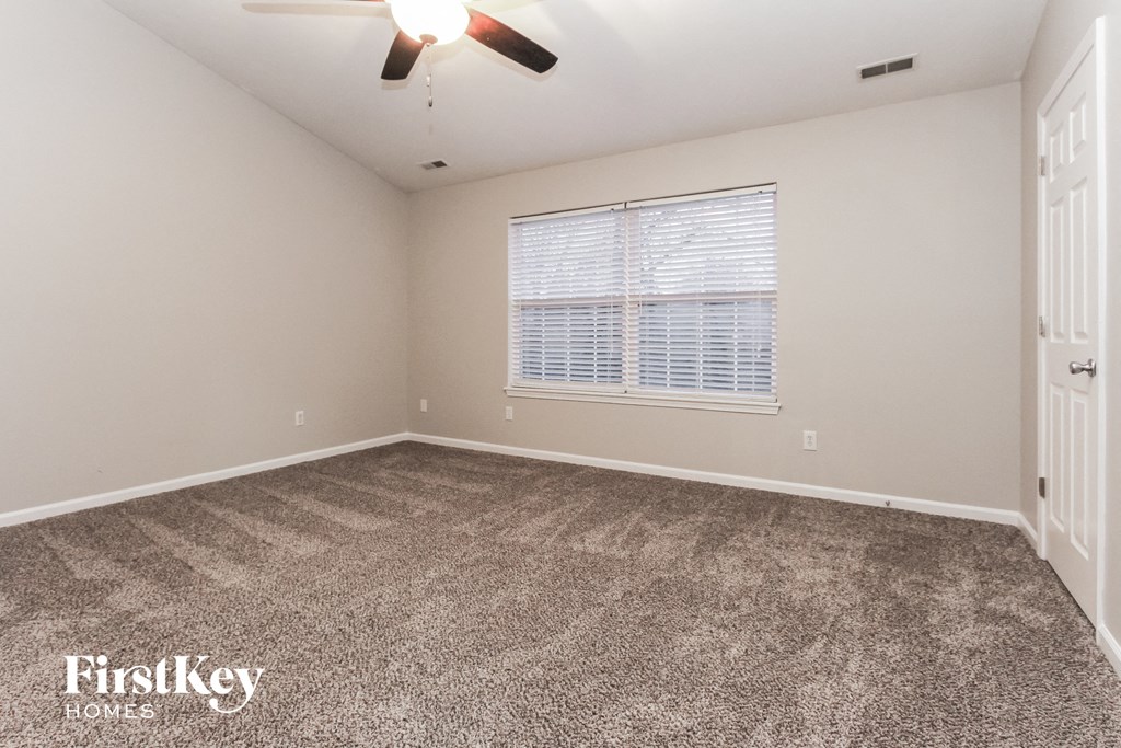 the living room of an empty house with carpet and a window