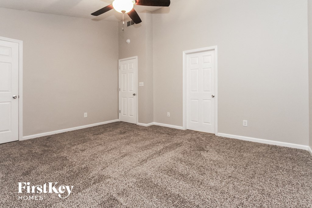 the living room of an empty house with carpet and a ceiling fan