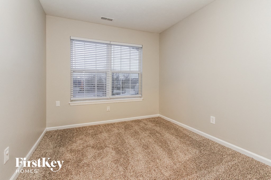 a spacious room with carpet and a window
