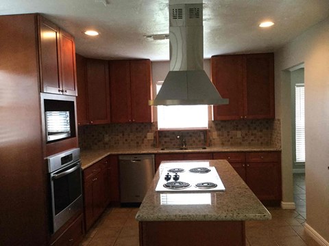 A kitchen with brown cabinets and a granite countertop.