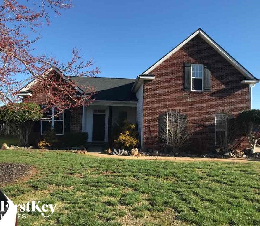a red brick house with green grass and a blue sky
