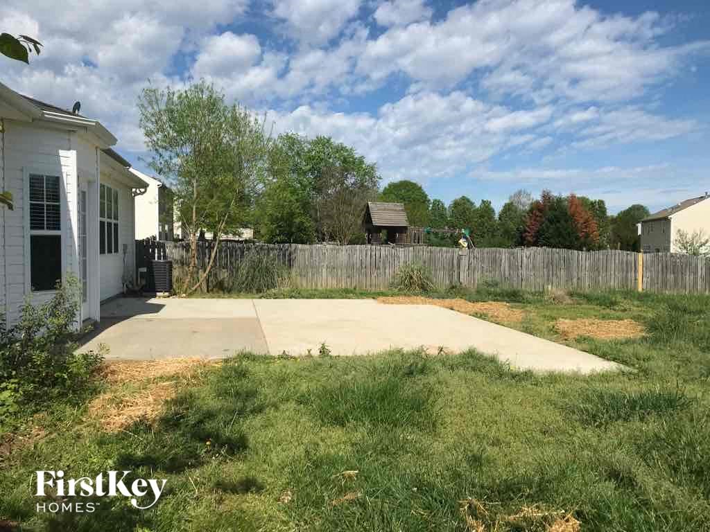 the backyard of a house with a concrete patio and a fence