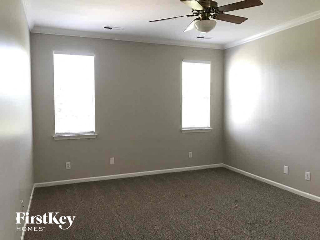a empty room with a ceiling fan and two windows