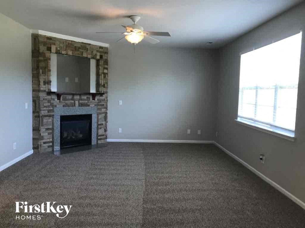 an empty living room with a fireplace and a ceiling fan