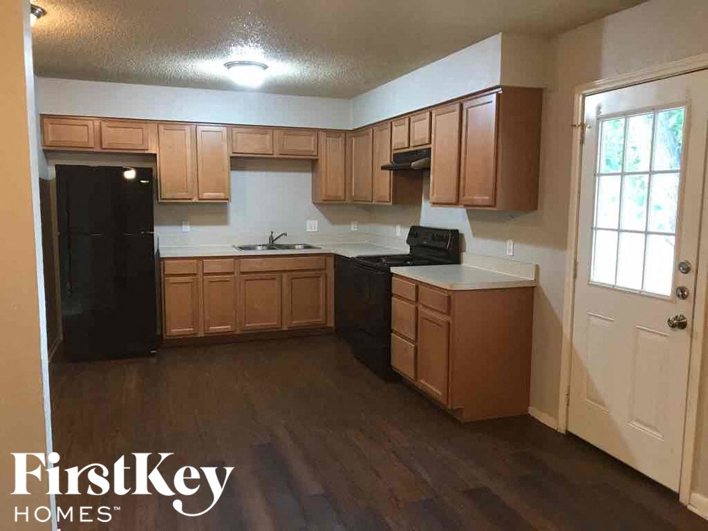 A kitchen with wooden cabinets and a black fridge.