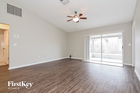 A spacious room with wooden flooring and a ceiling fan.
