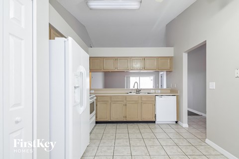A kitchen with a white refrigerator and cabinets.