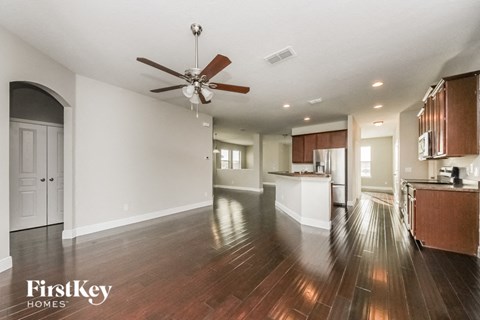 A spacious kitchen and living room with wooden floors and a ceiling fan.