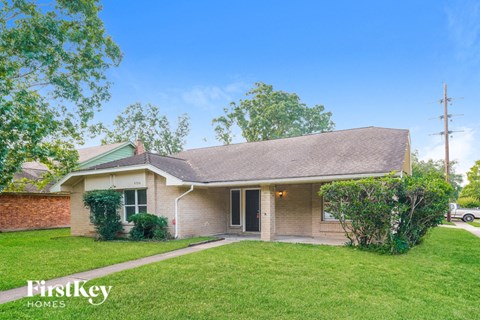 A house with a green lawn and a tree in front of it.
