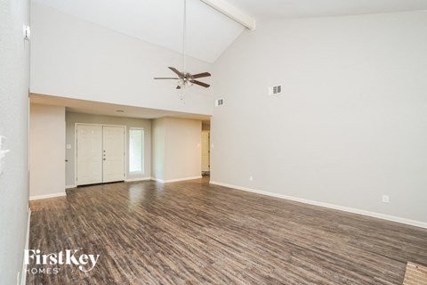 A spacious room with a ceiling fan and wooden flooring.