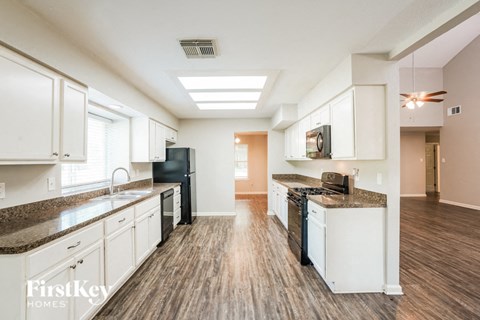 A kitchen with white cabinets and a black fridge.