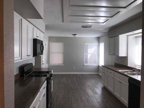 A kitchen with white cabinets and a black countertop.