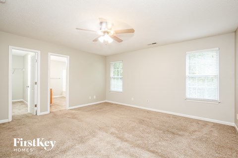 a spacious living room with carpet and a ceiling fan