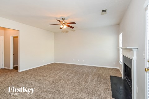 A room with a carpeted floor and a ceiling fan.