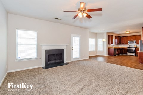 A spacious living room with a fireplace and a ceiling fan.