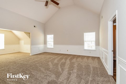 A spacious room with a carpeted floor and a ceiling fan.