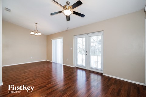an empty living room with wood floors and a ceiling fan