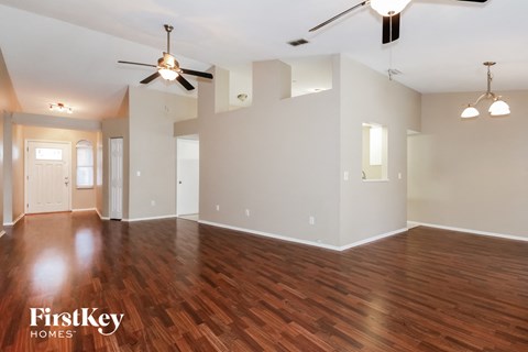 an empty living room with wood flooring and a ceiling fan