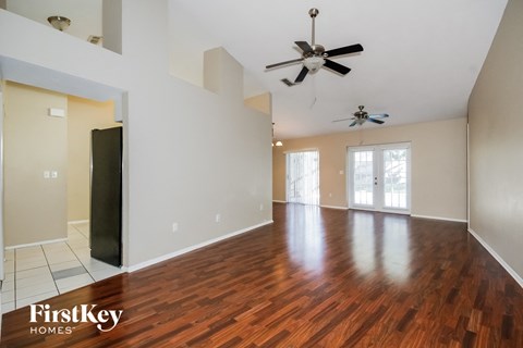 an empty living room with wood flooring and a ceiling fan