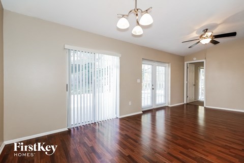 an empty living room with wood floors and a ceiling fan